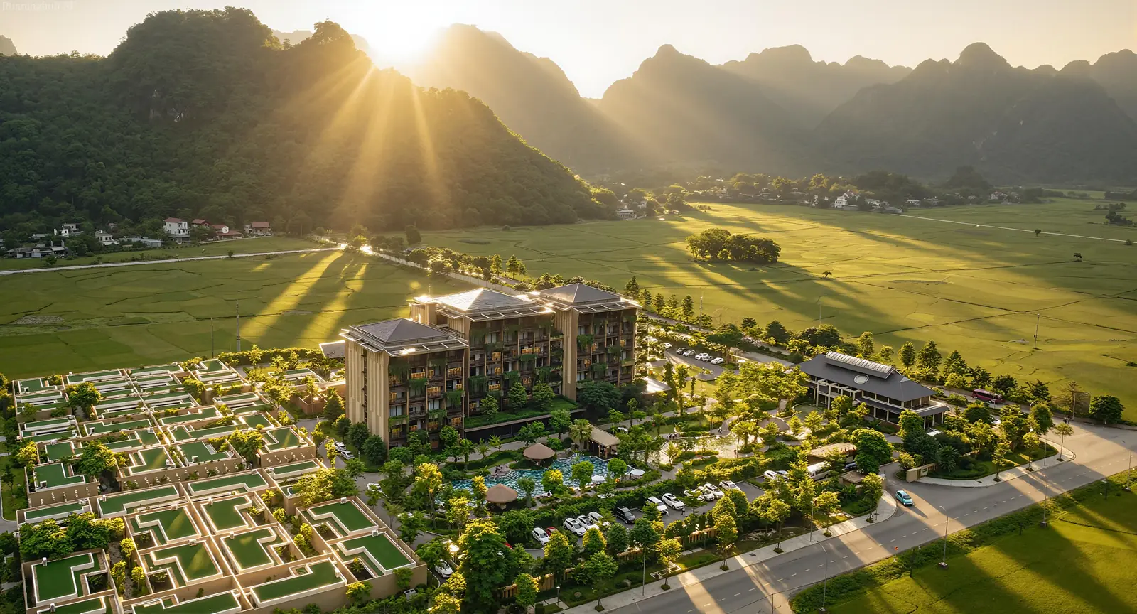 Mandala Retreats Kim Bôi nhìn từ trên cao lúc bình minh: tòa phòng nghỉ, dãy villa và bể bơi giữa cánh đồng lúa, phía sau là núi đá vôi