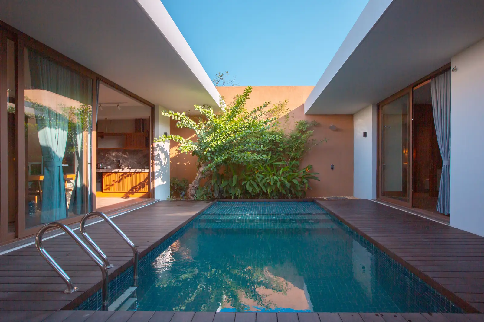 Bể bơi riêng trong sân villa La Minh, sàn gỗ và cây xanh hai bên