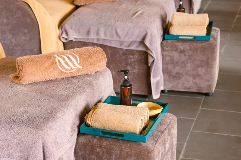 Ghế ngâm chân bọc nỉ ở La Zen Spa, khăn cuộn thêu logo Mandala và khay khăn