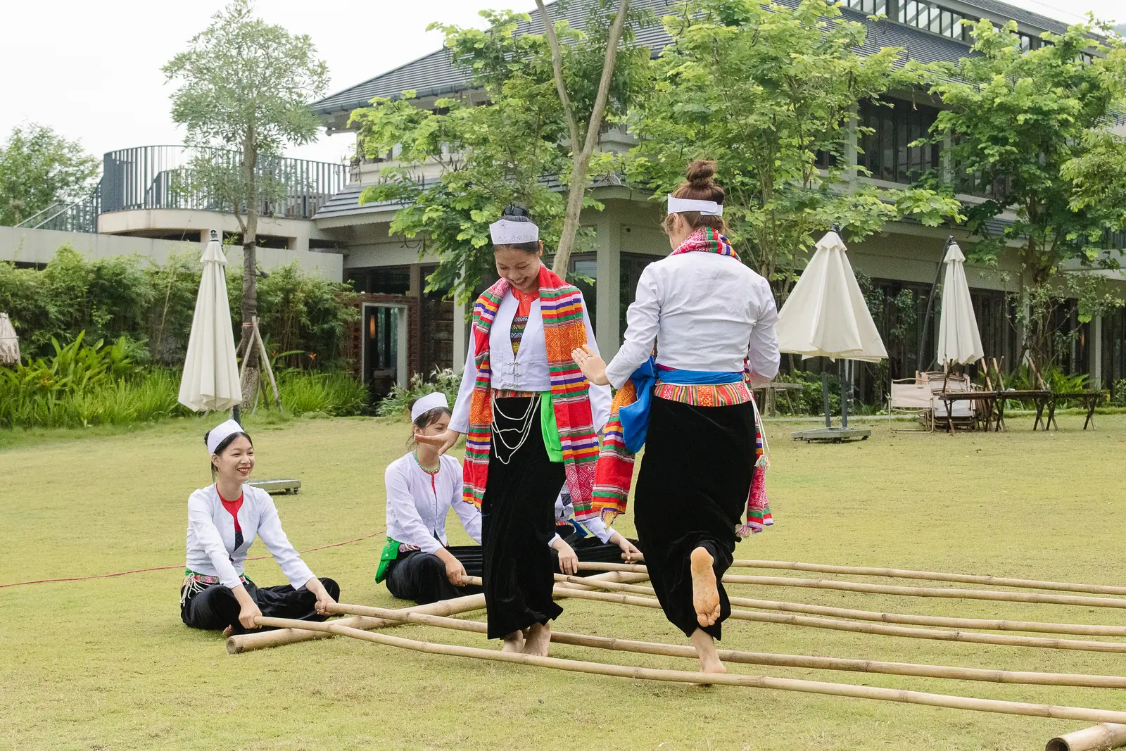 Nghệ nhân trong trang phục Mường múa sạp trên bãi cỏ trước khu nghỉ