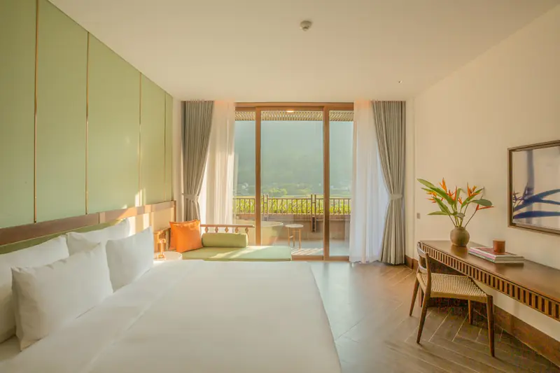 Phòng giường đôi rộng, sàn gỗ, cửa kính lớn mở ra ban công nhìn núi
