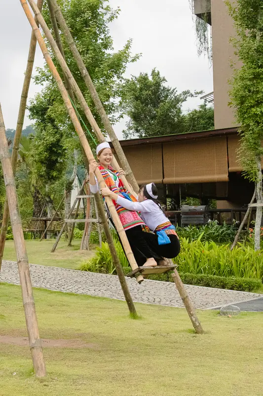 Hai cô gái mặc áo Mường cùng đánh đu trên cây đu tre giữa vườn