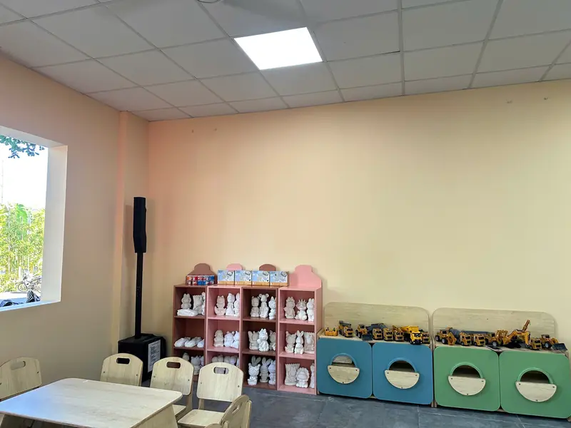 Góc tô tượng trong Kid's Club: kệ tượng thạch cao trắng, bàn ghế nhỏ và hộp đồ chơi