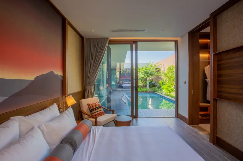 Phòng ngủ villa La Sen nhìn qua cửa kính ra bể bơi riêng và sân cây