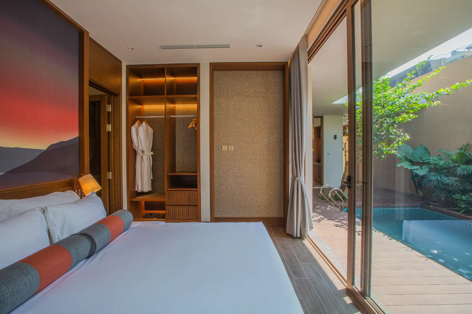 Phòng ngủ villa La Yên: giường đôi, tranh núi lúc hoàng hôn, tủ áo mở, cửa kính trượt ra bể bơi riêng